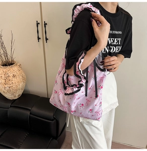 Detail of pink floral tote bag with black ruffle straps shown on model's shoulder