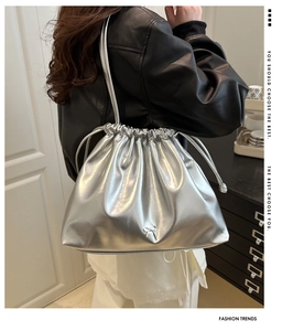 Détail du sac seau métallisé argenté avec petit nœud en métal et texture plissée élégante