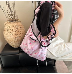 Detail of pink floral canvas bag with rose prints and black ruffle trim on shoulder