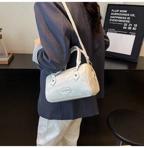 Detail of snake-embossed Boston bag with metal nameplate shown on model's shoulder