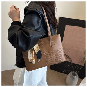Detail of retro brown patchwork tote bag with crocodile texture and silk scarf accessory