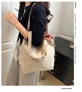 Detail of beige canvas tote bag with pink lining and drawstring closure on shoulder