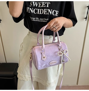 Detail of light purple Boston bag featuring faux snakeskin texture and pearl bow charm