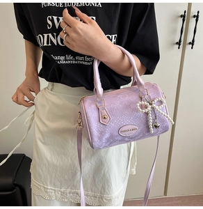 Détails d'un sac Boston violet clair avec texture crocodile et breloque nœud en perles