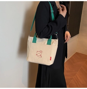 Detail of canvas tote bag showing cute cartoon print and red SPORT woven label detail