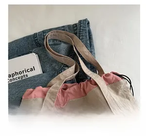 Detail of drawstring bucket bag showing pleated texture in beige and dusty rose contrast