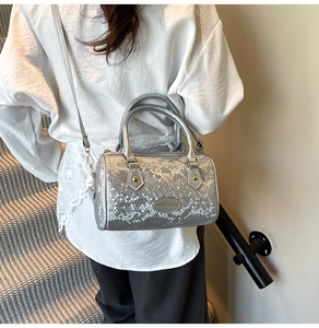Silver snakeskin embossed cylinder bag styled on model with a white shirt and gold accents