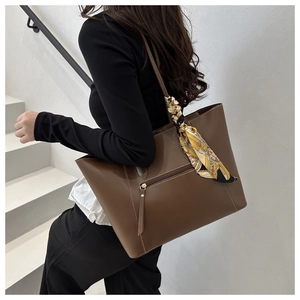 Macro detail of large brown tote bag with decorative silk scarf and side zipper pocket