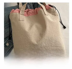 Detail of two-tone bucket bag featuring beige and pink textured fabric with drawstring