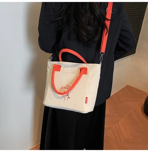 Detail of cream canvas bucket bag with orange straps and cute cartoon bear print