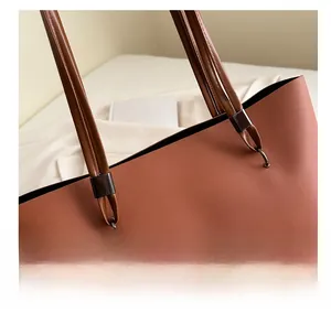 Détail de la anse du sac fourre-tout en cuir marron avec anneaux métalliques et texte FASHION