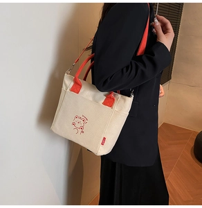 Detail of canvas tote bag featuring orange straps and cute cartoon bear print with Yummy text