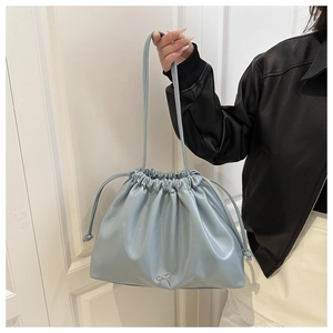 Detail of light blue bucket bag with drawstring closure and silver bow ornament
