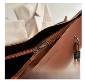 Gros plan sur la fermeture éclair en métal fluide d'un grand sac cabas en cuir marron