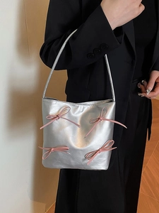 Silberne Bucket Bag mit rosa Schleifen an Model mit schwarzem Blazer getragen