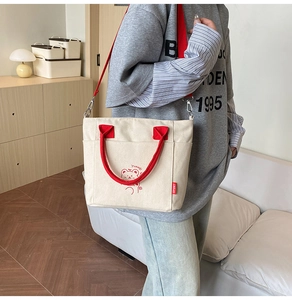 Detail der roten Riemen und Bärenprint auf cremefarbenem Canvas-Tote-Bag mit Schultergurt