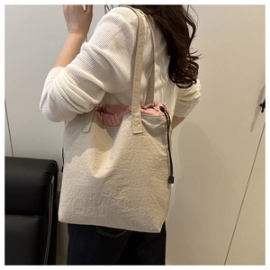 Detail of beige tote bag with pink drawstring lining and textured fabric finish