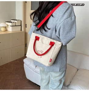 Detail of canvas bucket tote bag with red handles and cartoon animal print in a home setting
