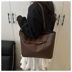 Close-up of matte leather texture and decorative strap on dark brown tote bag