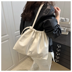 Dettaglio della borsa tote lucida bianca con coulisse e ciondolo a fiocco argento