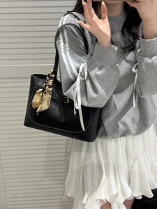 Classic black leather tote bag with white contrast stitching and decorative silk scarf