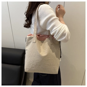 Detailed shot of large beige canvas bucket bag with pink drawstring lining and handles