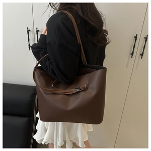 Detail view of large dark brown leather tote bag with slim shoulder straps and matte finish