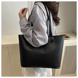 Detailed side view of minimalist black tote bag with slim shoulder straps and matte finish