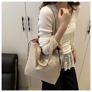 Detail of beige canvas tote bag showing the pink drawstring lining and adjustable cord