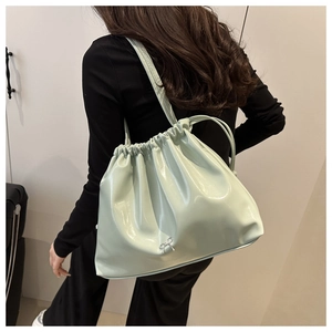 Close-up of mint green bucket bag featuring stylish drawstring pleats and a metal bow detail