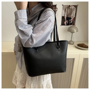 Detail of black leather tote bag with FASHION embossed logo and thin shoulder straps