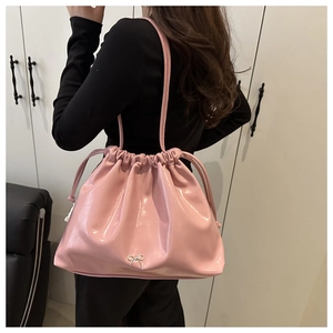 Detail view of pink patent leather tote bag with silver bow accent and drawstring closure