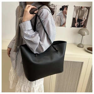 Close-up of minimalist black tote bag with long leather straps in a home interior setting