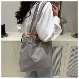 Grey tote bag with pink drawstring detail shown in a minimalist home setting