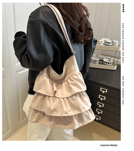 Rear view of model wearing a beige ruffled canvas tote bag with multi-layer frill design