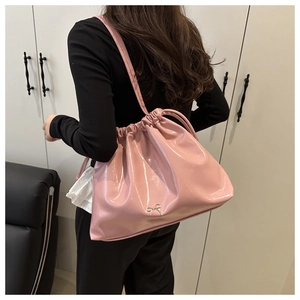Détail du sac cabas en cuir verni rose avec fermeture à cordon et nœud argenté décoratif