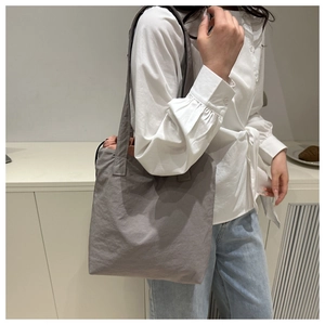 Detail of grey fabric bucket bag with drawstring closure and contrasting red inner lining
