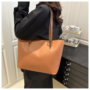 Detail of a large brown tote bag with FASHION logo and long handles on a model