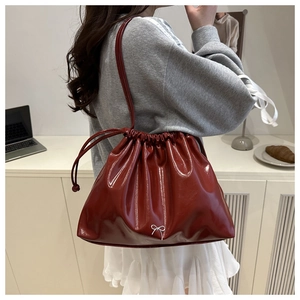 Détail du sac fourre-tout bordeaux en cuir verni avec nœud argenté et cordon de serrage