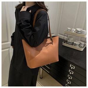 Sac fourre-tout en cuir marron avec logo FASHION porté à l'épaule dans un décor moderne