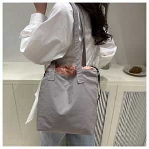 Detail of grey canvas tote bag with pink drawstring closure on a shoulder strap