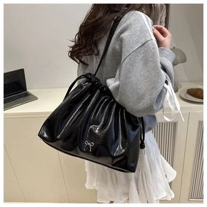 Dettaglio borsa tote in pelle nera lucida con fiocco argento e design a coulisse