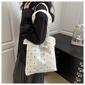 Close-up of white floral canvas tote bag with ruffle trim and brand label detail