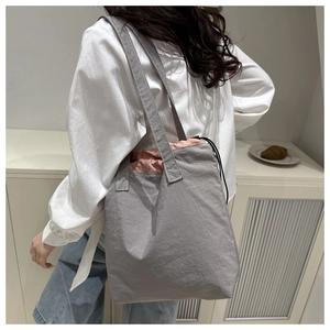 Detail of grey canvas tote bag featuring contrast pink drawstring closure and soft texture