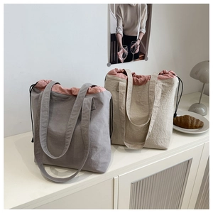 Detail view of grey and beige drawstring bucket bags with textured fabric in a cozy room