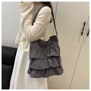 Close-up of grey ruffle canvas tote bag featuring layered frill design and long shoulder strap