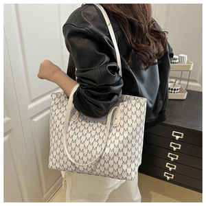 Detail of large tote bag featuring grey M-pattern print and slim white shoulder straps