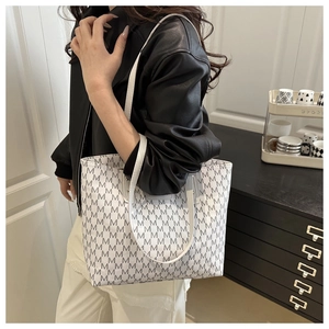 Detail of white tote bag with black M-letter pattern and dual shoulder straps