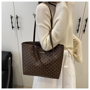 Detail of dark brown tote bag featuring all-over M monogram pattern and metal fashion logo