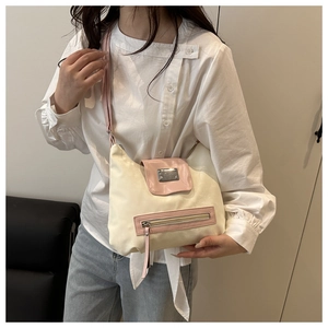 Detail of pink zipper pocket and metal buckle on cream faux leather shoulder bag